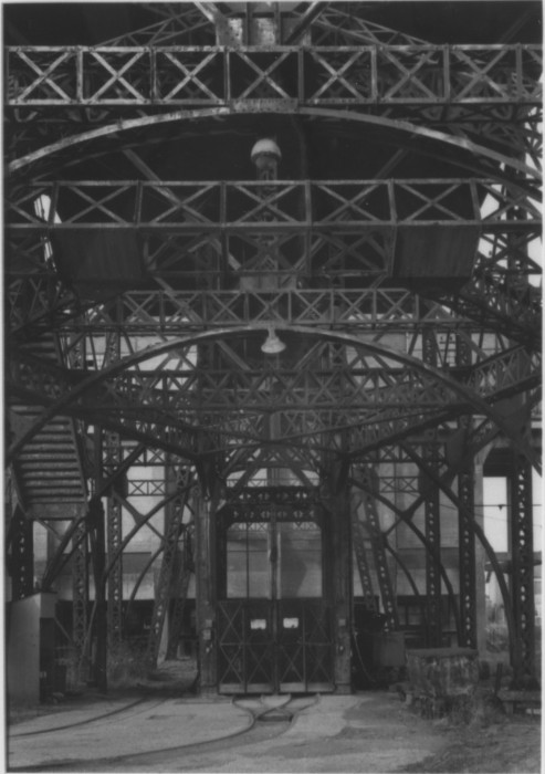 Black-and-white photograph of metallic ceiling arches and horizontal trusses.