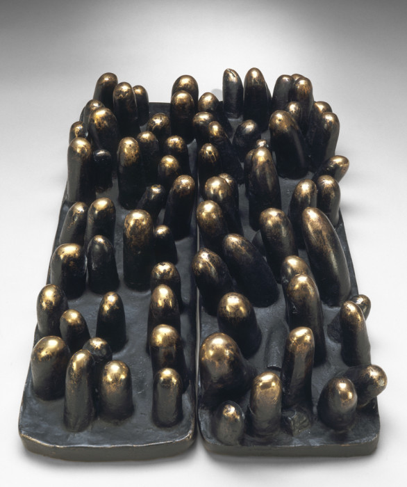 A rectangular, black base is topped with bronze cylindrical forms and placed next to a nearly identical object.