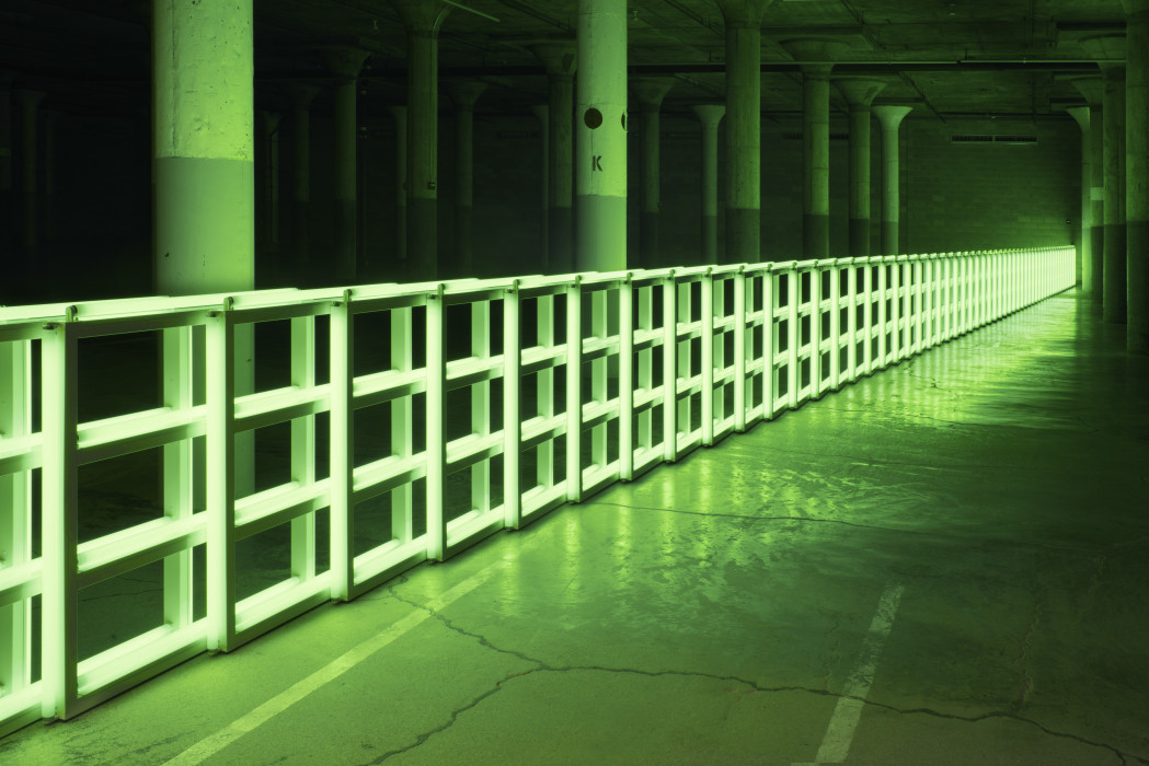 A green fluorescent barrier spans a large dark room with pillars.