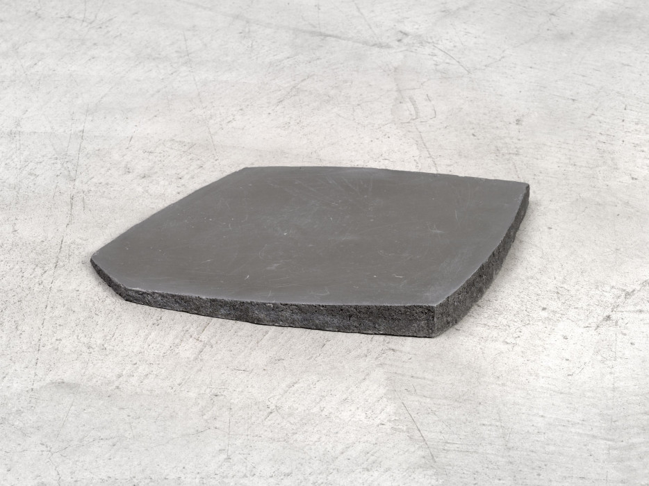 A close up of a dark grey irregular slab on concrete floor.