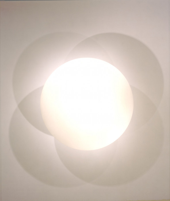A central, circular, bright shape casts four intersecting shadows on a nondescript background.
