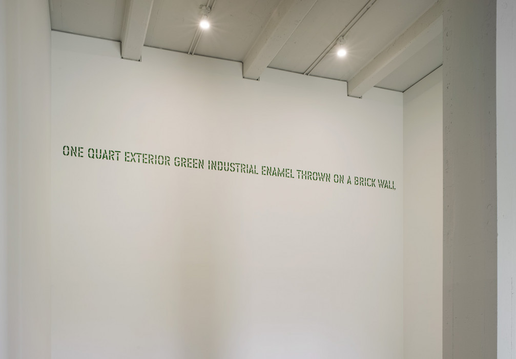 Green stenciled text placed high on a white wall reads: 