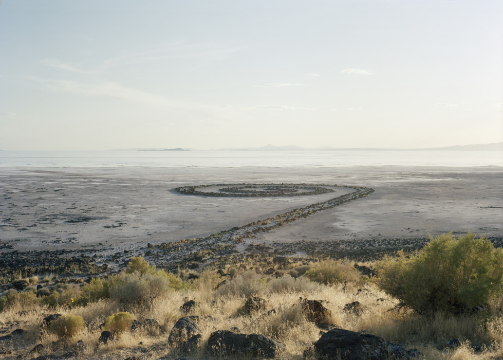 A large spiral made of rocks juts out from the shore of the Great Salt Lake and turns counterclockwise on the bottom of the lake.
