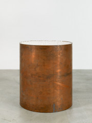 A large copper tube-shaped vessel containing large chunks of salt. The copper is worn with various marks and smudges.