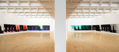 A view of a large gallery lined with many iterations of the same print, bisected by a white pillar in the foreground. On the left, the prints are in black, red, peach, pink, and blue, while on the right the prints are in black, white, grey, and aqua.