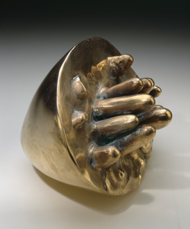 A cone-like, bronze shape is placed on its side with cylindrical forms of various sizes emerging from its flatter end.
