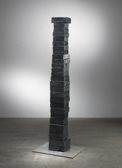 A stack of twenty-seven bronze blocks of different sizes rests above a thin stainless-steel platform.