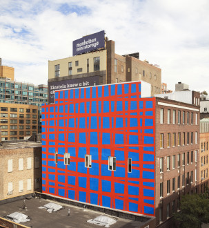 The side of a building painted in a blue with a red grid.