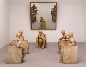 Five sculpted figures sit on square armchairs in an evenly spaced horseshoe formation. The four foreground figures are in conversation with each other. The fifth figure in the background has head turned away and looks into a mirror that reflects all five figures.