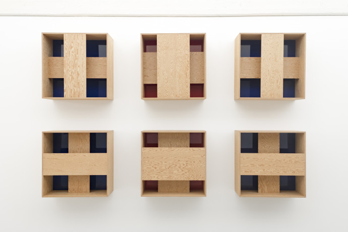 6 wooden boxes, each has 2 strips of wood forming a cross over a red or blue interior.
